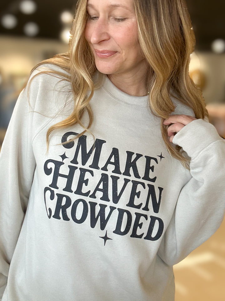 Person wearing a white sweatshirt with 'MAKE HEAVEN CROWDED' text.
