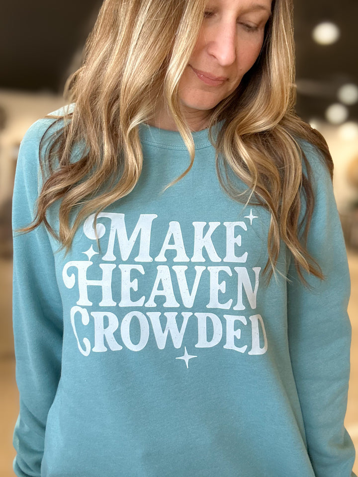 Person wearing a teal sweatshirt with 'MAKE HEAVEN CROWDED' text.