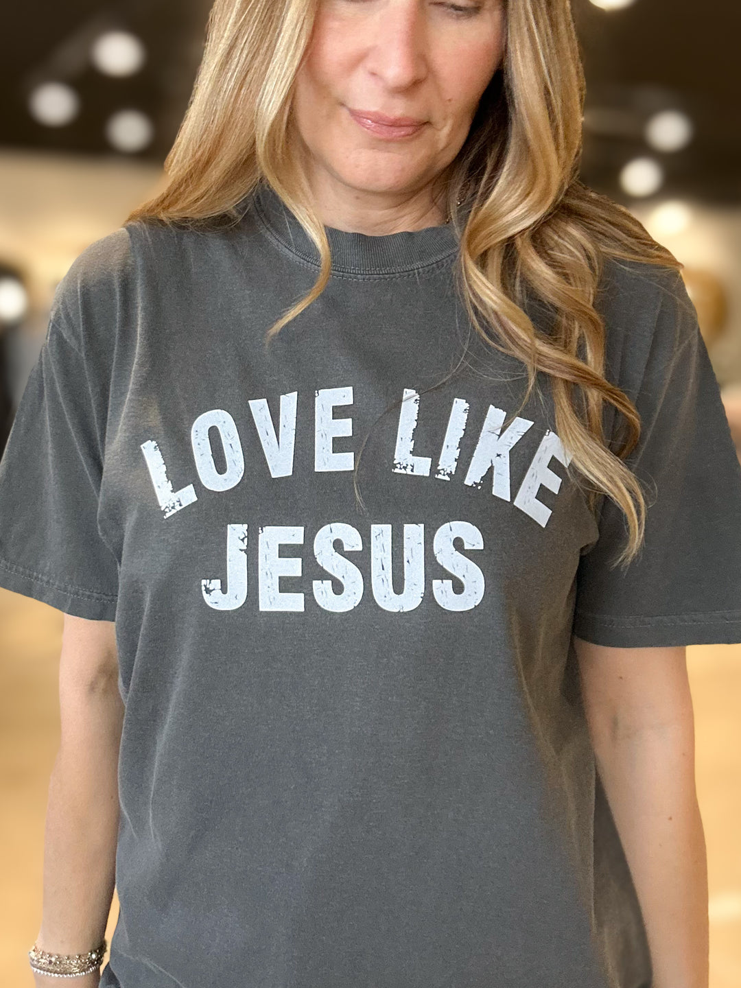 Person wearing a gray t-shirt with 'LOVE LIKE JESUS' text.